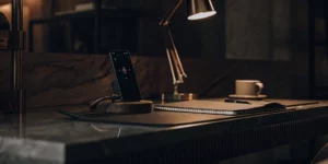 Business phone answering setup with smartphone, notepad, and pen.