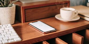 Business phone setup on a desk with smartphone, keyboard, and coffee.